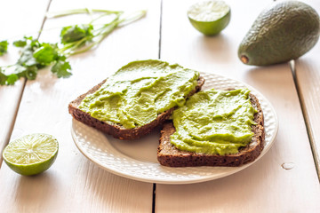 Sandwiches with avocado on the white wooden background.