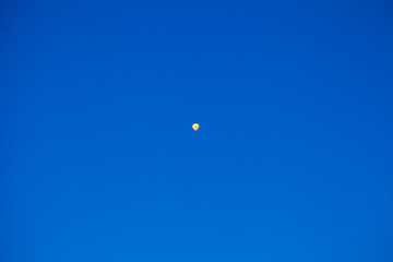 Yellow hot air balloon flying very high in the blue sky