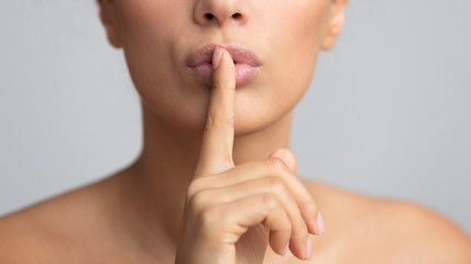 Silent gesture. Woman holding finger on lips