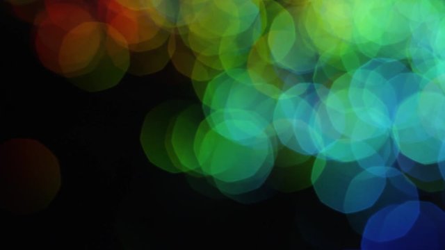 Multicolored spots of shiny bokeh on black background. Stock footage. Colorful bright shiny large bokeh beautifully shine on black background