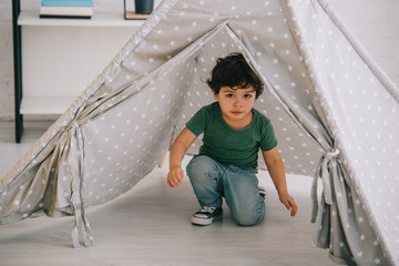 cute kid in jeans sitting in grey wigwam at home © LIGHTFIELD STUDIOS