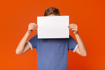 Little boy holding an blank card in front of his head