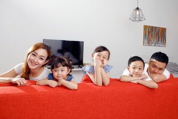 Parent mother father little child boy girl brother sister happy smile looking over the sofa