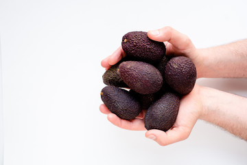 Avocado in the hands of a man on a light background. Healthy food and lifestyle. For lovers of avocado and vegetarians. Avocado closeup. Ready to eat. Nutrition and diet concept. Eco product