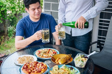 Two young man hand raise a glass of beer to celebrate the holiday festival happy drinking beer outdoors and enjoying at home