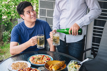 Two young man hand raise a glass of beer to celebrate the holiday festival happy drinking beer outdoors and enjoying at home