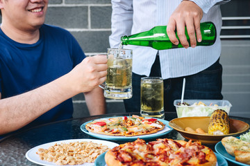 Two young man hand raise a glass of beer to celebrate the holiday festival happy drinking beer outdoors and enjoying at home