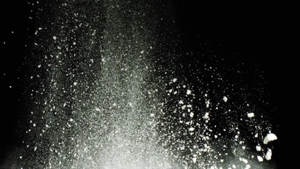 Explosion of white flour on black background. Stock footage. Explosion of thick cloud of white powder with crumbling particles on black isolated background