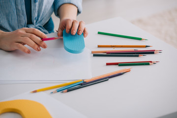 Cropped view of woman with color pencils and papers