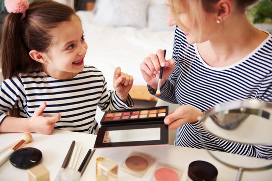 Mother and daughter applying make up together, using blusher