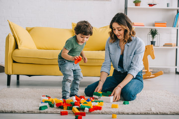 Mother and son playing with Bricks on carpet in living room