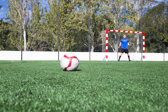 Football on grass with goalkeeper in the background