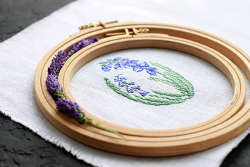embroidery on fabric, embroidery hoop, flowers, pins on a dark background, needlework concept