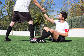 Football player helping an injured player during a match