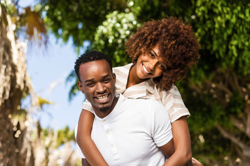 Outdoor protrait of black african american couple - Guy carrying girfriend on his back