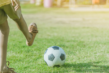 Asian boys practice kicking the ball to score goals in the public football field.