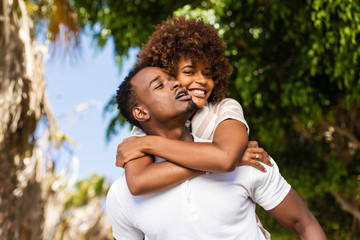 Outdoor protrait of black african american couple - Guy carrying girfriend on his back