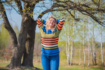 Nice woman in knitted sweater and jeans at forest. Concept of plus size woman, modern beauty and fashion 