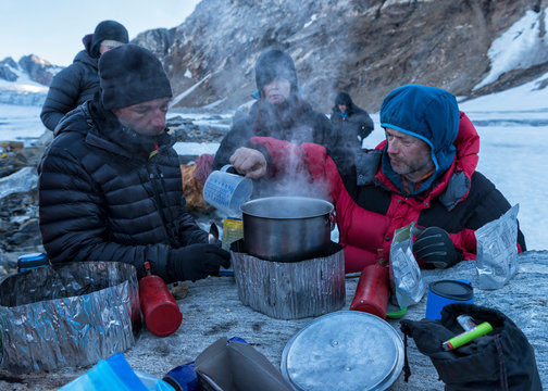 Greenland, Sermersooq, Kulusuk, Schweizerland Alps, group of people having a break cooking water