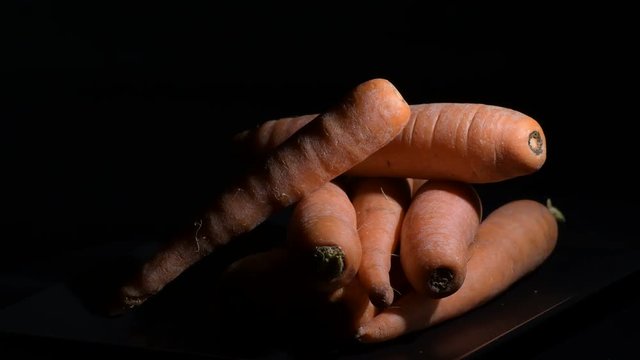 Natural carrots gyrating on black background. Daucus carota