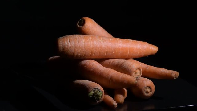 Carrots vegetables in a pile gyrating with black background. Daucus carota