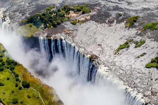 Victoria Falls from aerial view. Waterfall in southern Africa on the Zambezi River at the border between Zambia and Zimbabwe. Rainbow on the river. 
