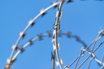 Barbed wire of a fence against blue sky