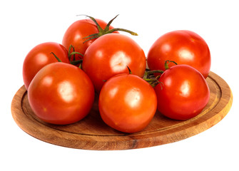 ripe red tomatoes on a round wooden cutting board. white background