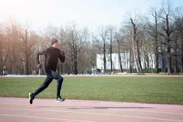 Fototapeta premium Photo of sports man running through stadium during spring jog