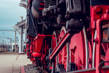 Perspective view of massive red steam train wheels – Vintage and classic mean of transport in a station – Old looking heavy industrial metallic machine