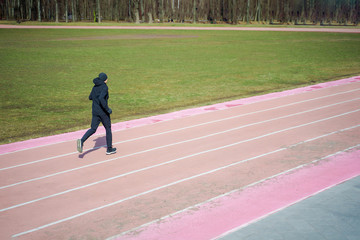 Photo of sports male running through stadium during spring jog.