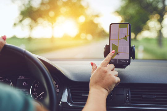 Close-up Of Woman Using GPS Navigation In Mobile Phone While Driving Car At Sunset