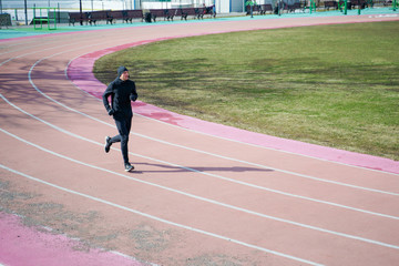 Photo of athlete man running through stadium during spring jog.
