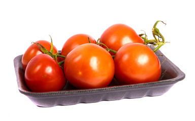 ripe red tomatoes in a dark plastic tray. on a white background