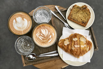 Milk coffee with croissant and bread and water on wooden table