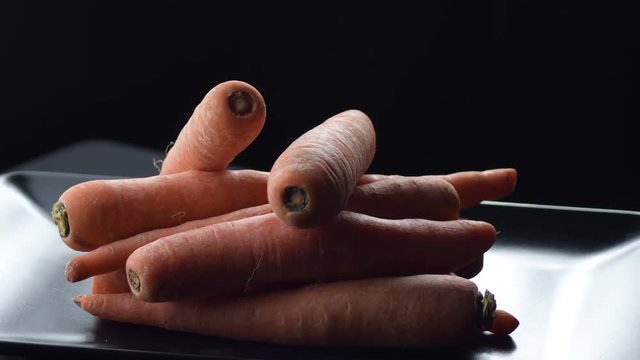 Raw natural carrots gyrating on a black tray. Daucus carota