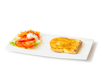 Ham and cheese grilled sandwich with salad in a rectangular white dish