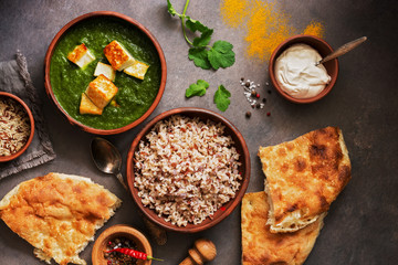 Indian food Palak Paneer , naan bread, rice and spices on a dark background. Overhead view. flat lay