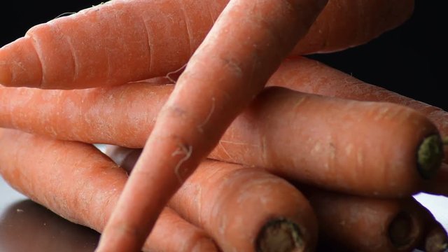 Raw carrots gyrating on a black tray. Daucus carota