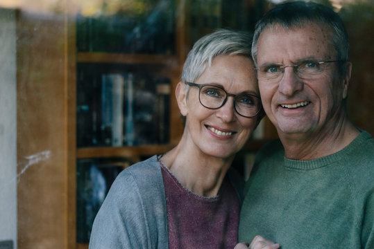 Portrait of happy senior couple behind windowpane