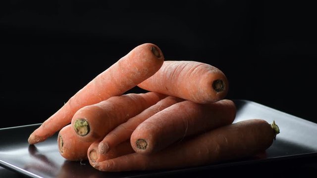 Natural carrots gyrating on a black tray. Daucus carota