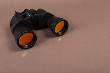 binoculars with orange lens on pastel background