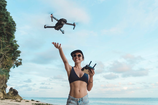 Indonesia, Bali, Nusa Dua, woman flying drone at the beach