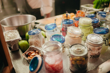 Jars with Pickled Vegetables and other Fresh Ingredients on Inox Table in a Hotel Restaurant Professional Kitchen