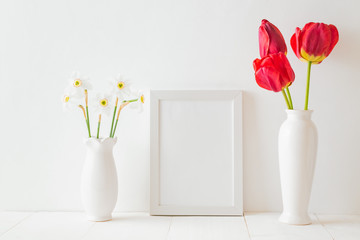 Mockup with a white frame and red tulips in a vase on a white wooden table