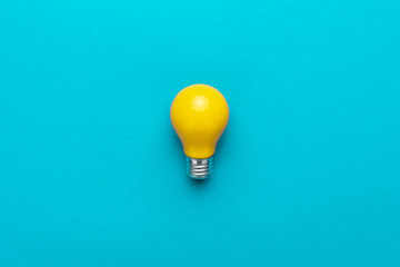 flat lay minimalist photo of yellow painted bulb on turquoise blue backgound