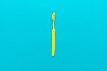 minimalist flat lay photo of yellow toothbrush over turquoise blue background