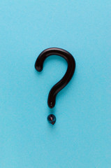 question mark from black toothpaste on blue background