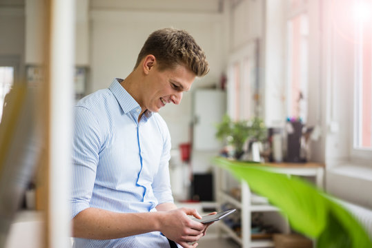 Smiling young businessman using tablet in office