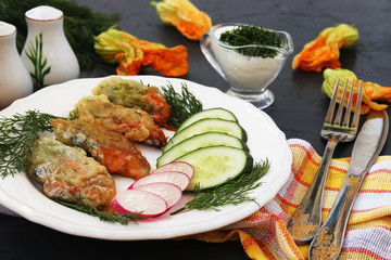 Fototapeta na wymiar Flowers of zucchini, cooked in batter, slices of cucumbers and radishes on a plate